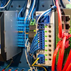 Industrial power supply and network switch components, part of a protective distribution system, with red Ethernet cables connected.