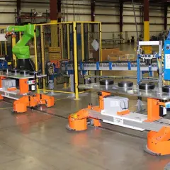Automated guided vehicles and a robotic arm work together in a factory setting, showcasing advanced fori automation.