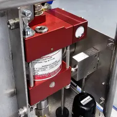 Close-up of a red liquid pump, likely a pneumatic pump, mounted on a stainless steel frame.