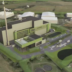An aerial view of a modern industrial facility, likely a waste-to-energy plant, designed by Valmet Inc. The complex features a tall smokestack, large grey and green buildings, a parking lot with trucks, and surrounding green spaces.
