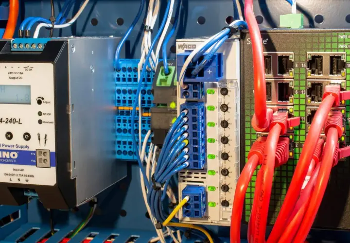 Industrial power supply and network switch components, part of a protective distribution system, with red Ethernet cables connected.