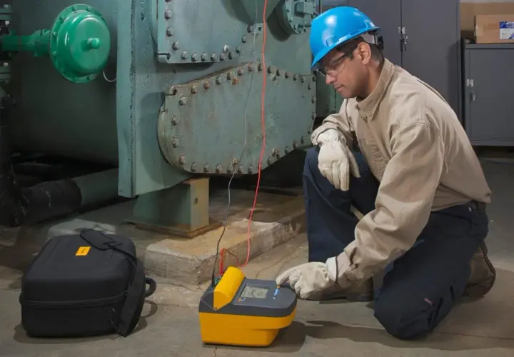 Technician uses a megohmmeter, a meter used to measure insulation resistance, on industrial equipment.