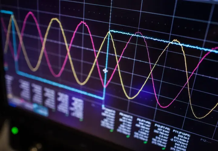Oscilloscope screen showing three waveforms (pink, yellow, blue) and data readouts, illustrating signal integrity analysis.