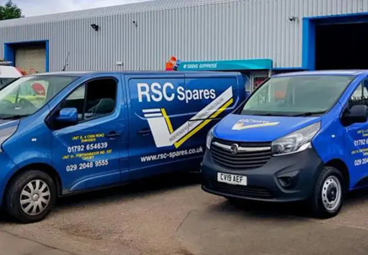Two blue vans from T&B Motors, branded RSC Spares, are parked outside a warehouse.
