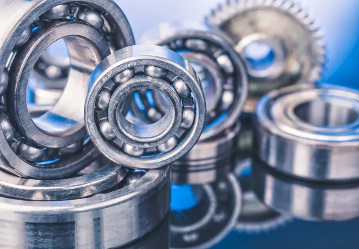 A close-up of several ball bearings, some with visible steel balls, on a reflective blue surface. These precision components, like glacier garlock bearings, are essential for smooth rotation.