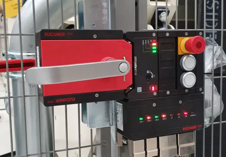 A red and silver Euchner MGB safety handle lock is mounted on a metal cage. The control unit shows green and red indicator lights.