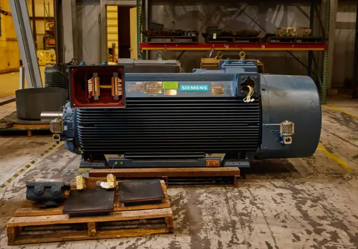 A large Siemens motor with its terminal box open, revealing wiring. Different motor enclosure types are visible in the background.