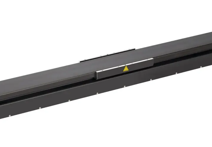 A long, black linear stage actuator with warning symbols.