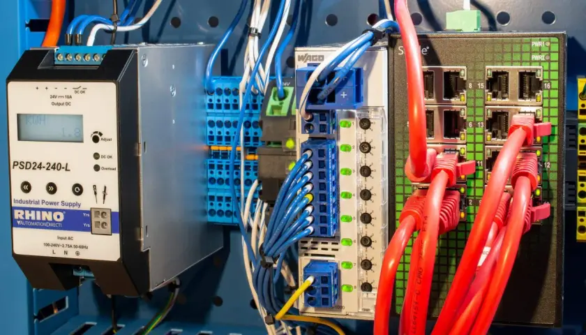 Industrial power supply and network switch components, part of a protective distribution system, with red Ethernet cables connected.