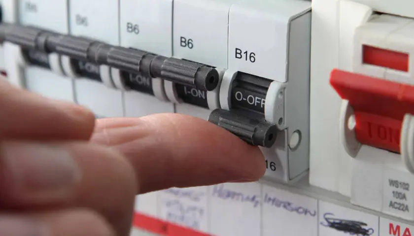 A finger flips a circuit breaker switch to the OFF position. This action might be taken if a circuit breaker fuse blown, indicating an overload or fault.