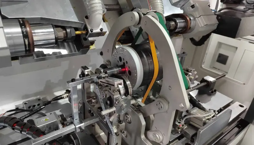 Precision machinery for electric motor balancing, featuring a spinning rotor with a red laser guide and automated arms.