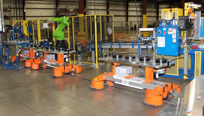Automated guided vehicles and a robotic arm work together in a factory setting, showcasing advanced fori automation.