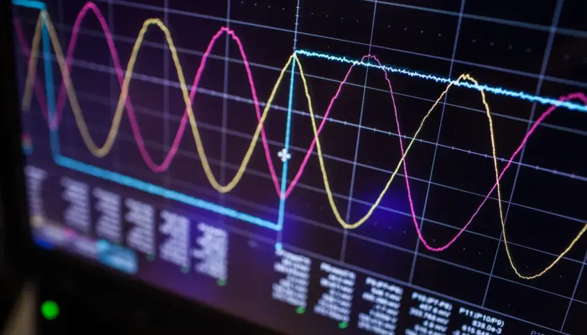 Oscilloscope screen showing three waveforms (pink, yellow, blue) and data readouts, illustrating signal integrity analysis.
