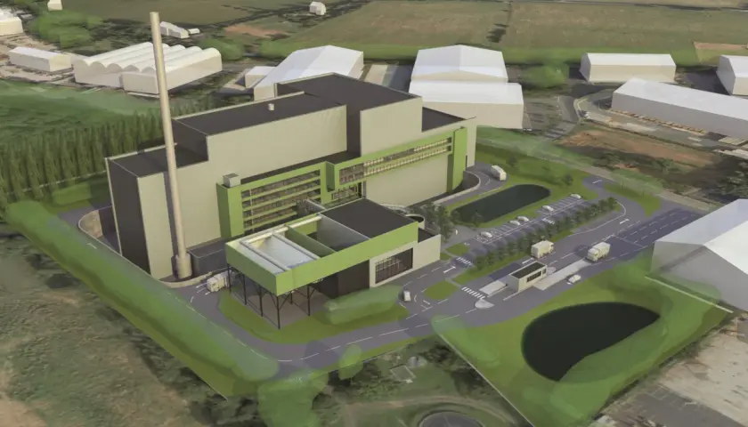 An aerial view of a modern industrial facility, likely a waste-to-energy plant, designed by Valmet Inc. The complex features a tall smokestack, large grey and green buildings, a parking lot with trucks, and surrounding green spaces.