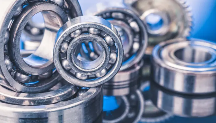 A close-up of several ball bearings, some with visible steel balls, on a reflective blue surface. These precision components, like glacier garlock bearings, are essential for smooth rotation.