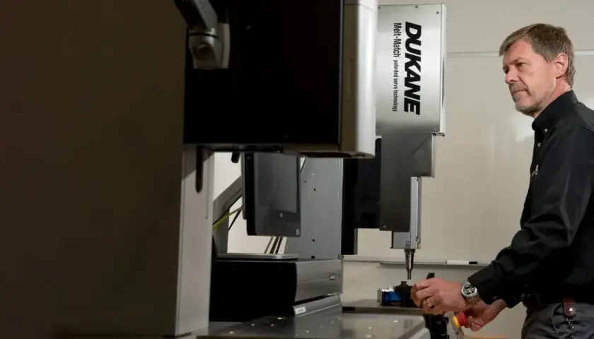 Man operating a Dukane Corporation Melt-Match ultrasonic welding machine.