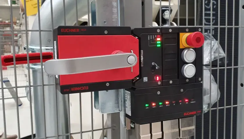 A red and silver Euchner MGB safety handle lock is mounted on a metal cage. The control unit shows green and red indicator lights.