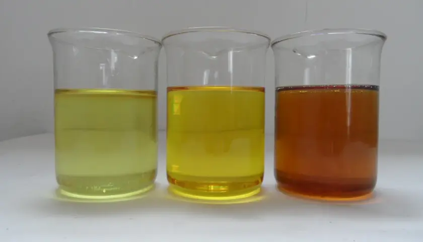 Three beakers contain liquids of varying shades of yellow and amber, representing different grades of iso oil.