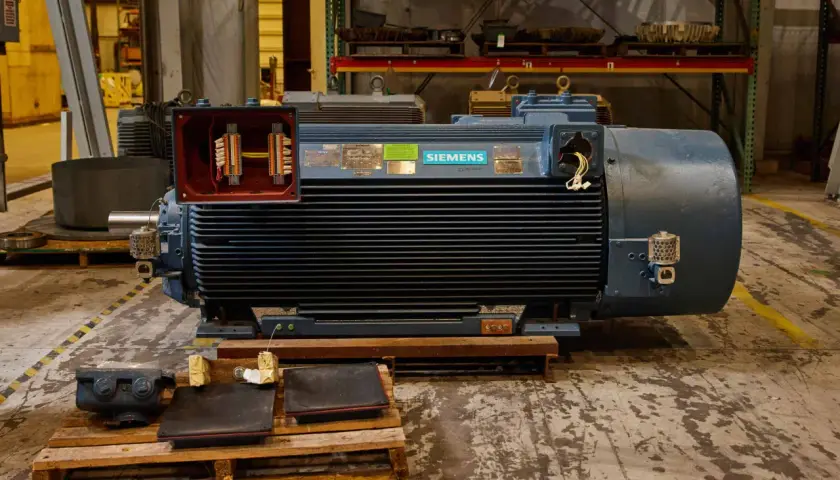 A large Siemens motor with its terminal box open, revealing wiring. Different motor enclosure types are visible in the background.