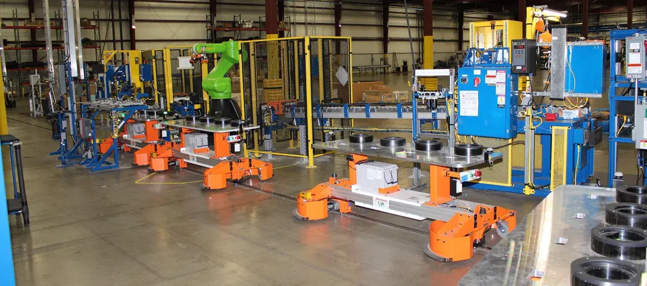Automated guided vehicles and a robotic arm work together in a factory setting, showcasing advanced fori automation.