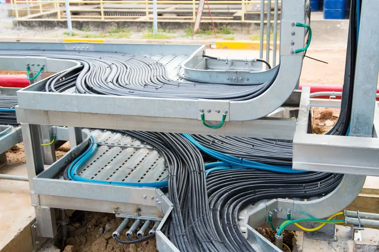A complex network of black and blue cables is neatly organized within metal tray cable systems, showcasing industrial cable management.