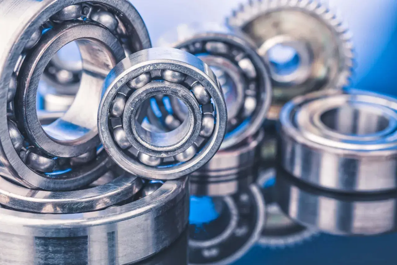 A close-up of several ball bearings, some with visible steel balls, on a reflective blue surface. These precision components, like glacier garlock bearings, are essential for smooth rotation.