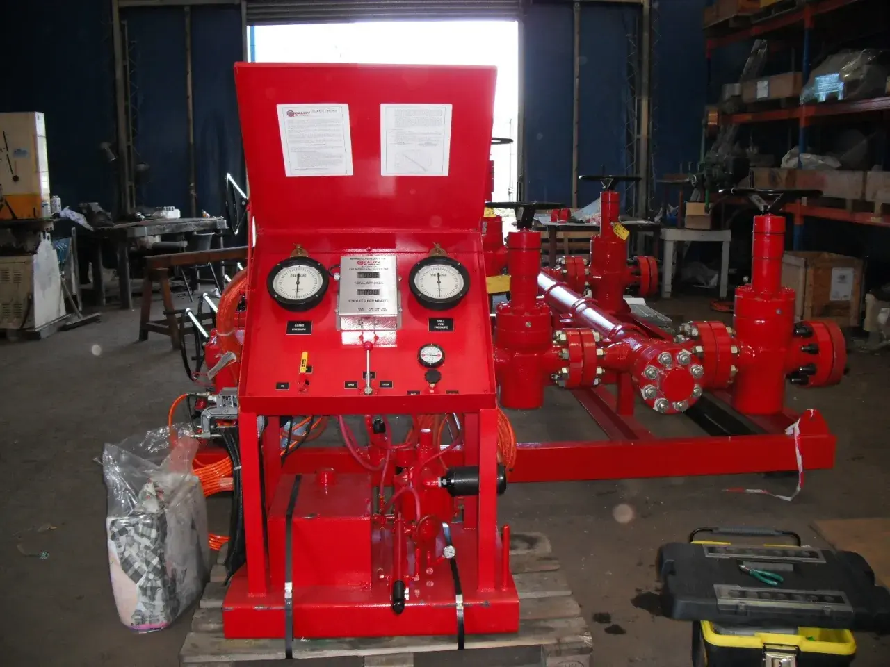 Red industrial equipment with gauges displaying pressure and flow velocity units.