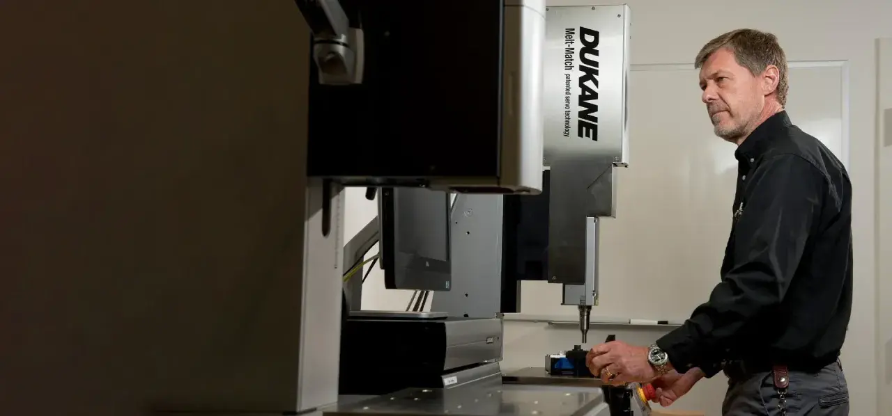 Man operating a Dukane Corporation Melt-Match ultrasonic welding machine.