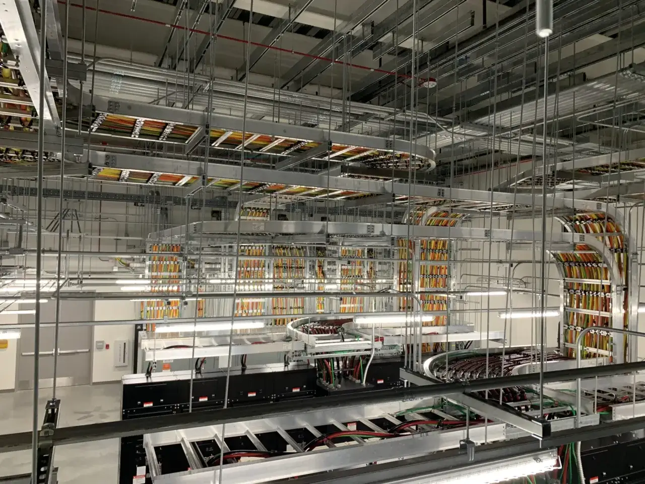 A complex network of tray cable systems, organizing bundles of colorful wires overhead in a modern facility.