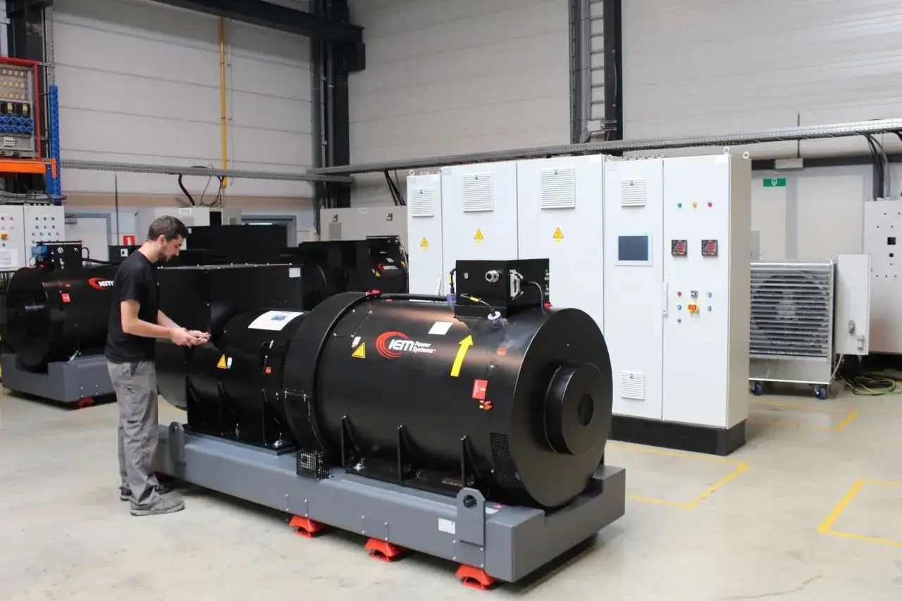Technician inspects a large black generator, part of a suite of industrial power systems by IEM Power Systems, in a clean, modern facility.