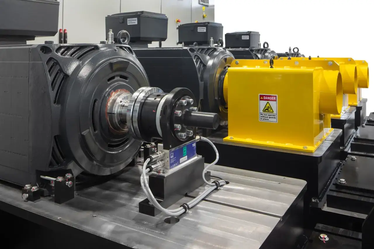 Industrial motors and yellow safety guards, likely part of a TMEIC Corporation testing setup.