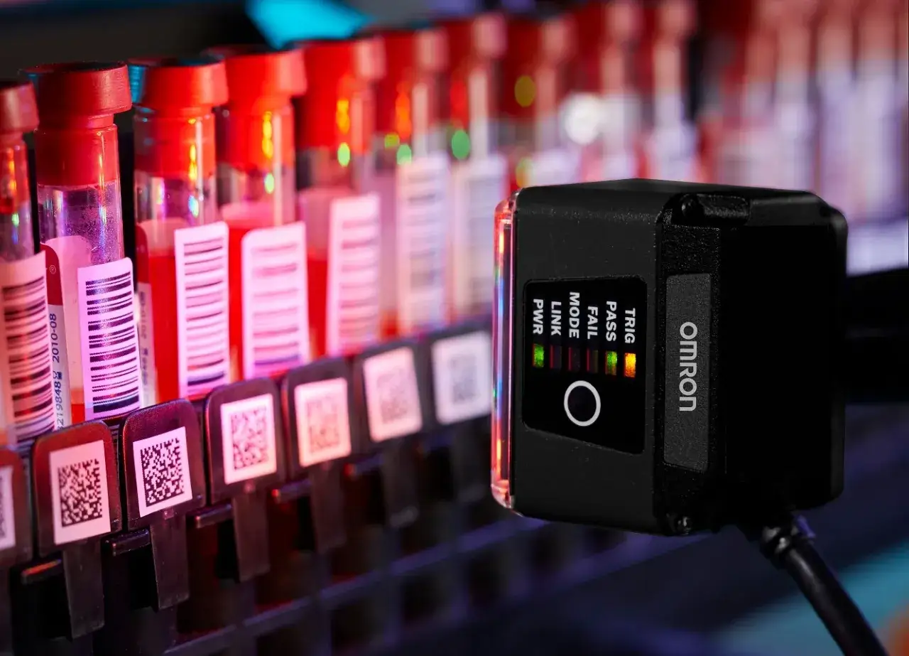 An Omron Microscan scanner reads barcodes on test tubes in a lab.