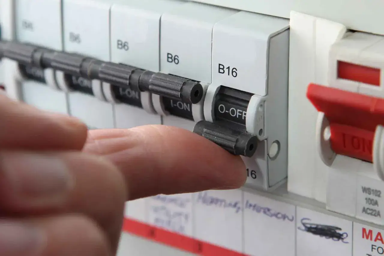 A finger flips a circuit breaker switch to the 